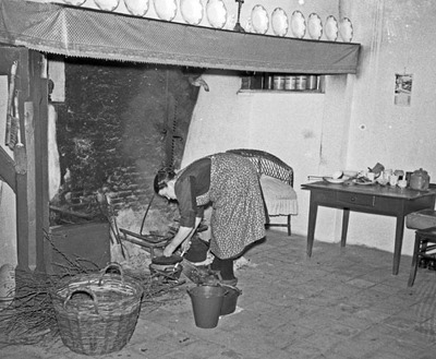 Foto gemaakt in 1955. Volgens de Heemkundekring 'Ledevaert' in Chaam, die dit in 2013 heeft uitgezocht, is dit Sjoke Jansen in haar boerderij aan de Grazenseweg in Strijbeek. Anno 2013 woont in deze boerderij volgens de heemkundekring een makelaar.