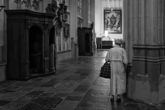 een oude vrouw is voor het gebed in de kathedraal